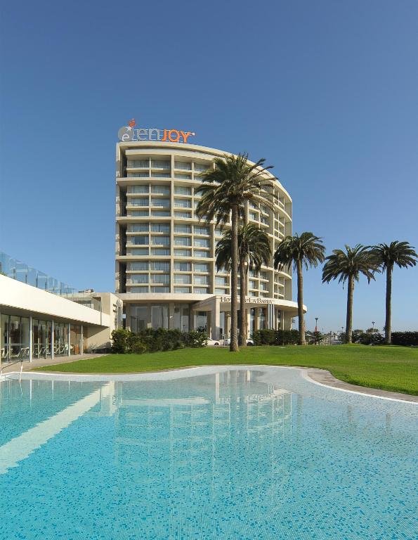Torre de hotel com palmeiras e piscina em primeiro plano
